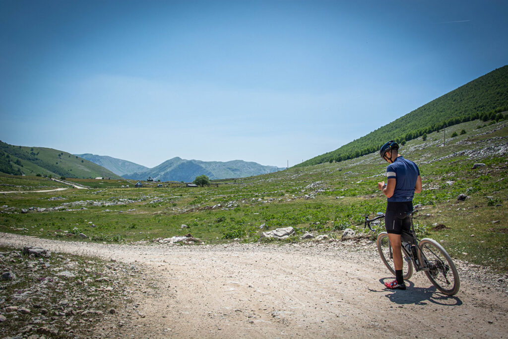 Mountainbiker in de bergen van Bosnië en Herzegovina die zijn Garmin gebruikt om een MTB-route te navigeren.